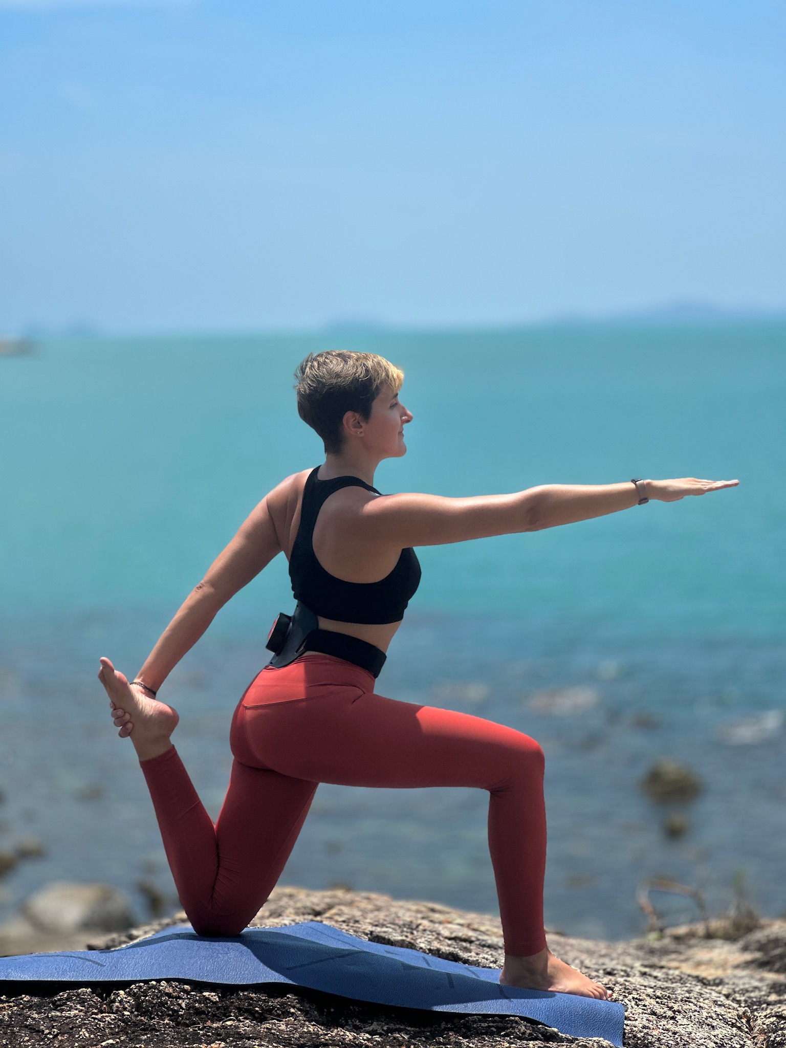 Athlete in low-lunge stretch overlooking ocean — recovery and mobility work